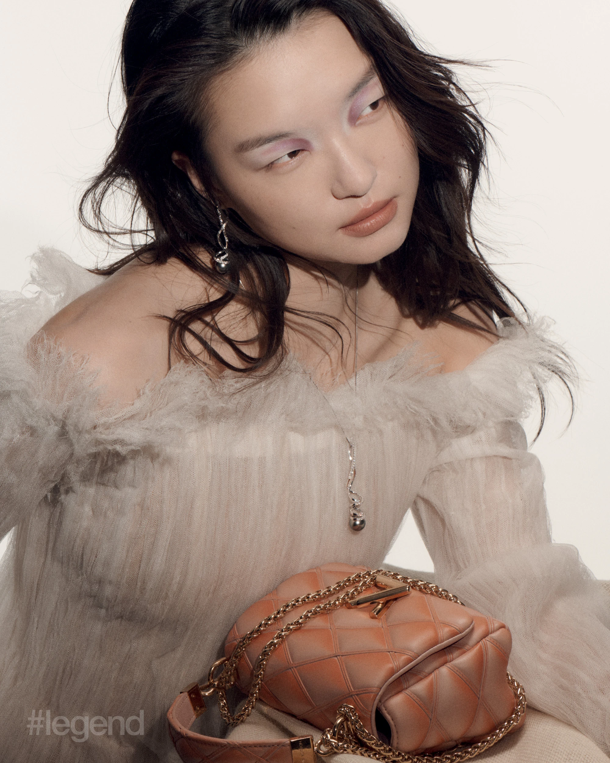 Earrings and necklace in white gold with black South Sea cultured pearls and diamonds _ Mikimoto; White off-the-shoulder dress and brown leather bag _ Louis Vuitton