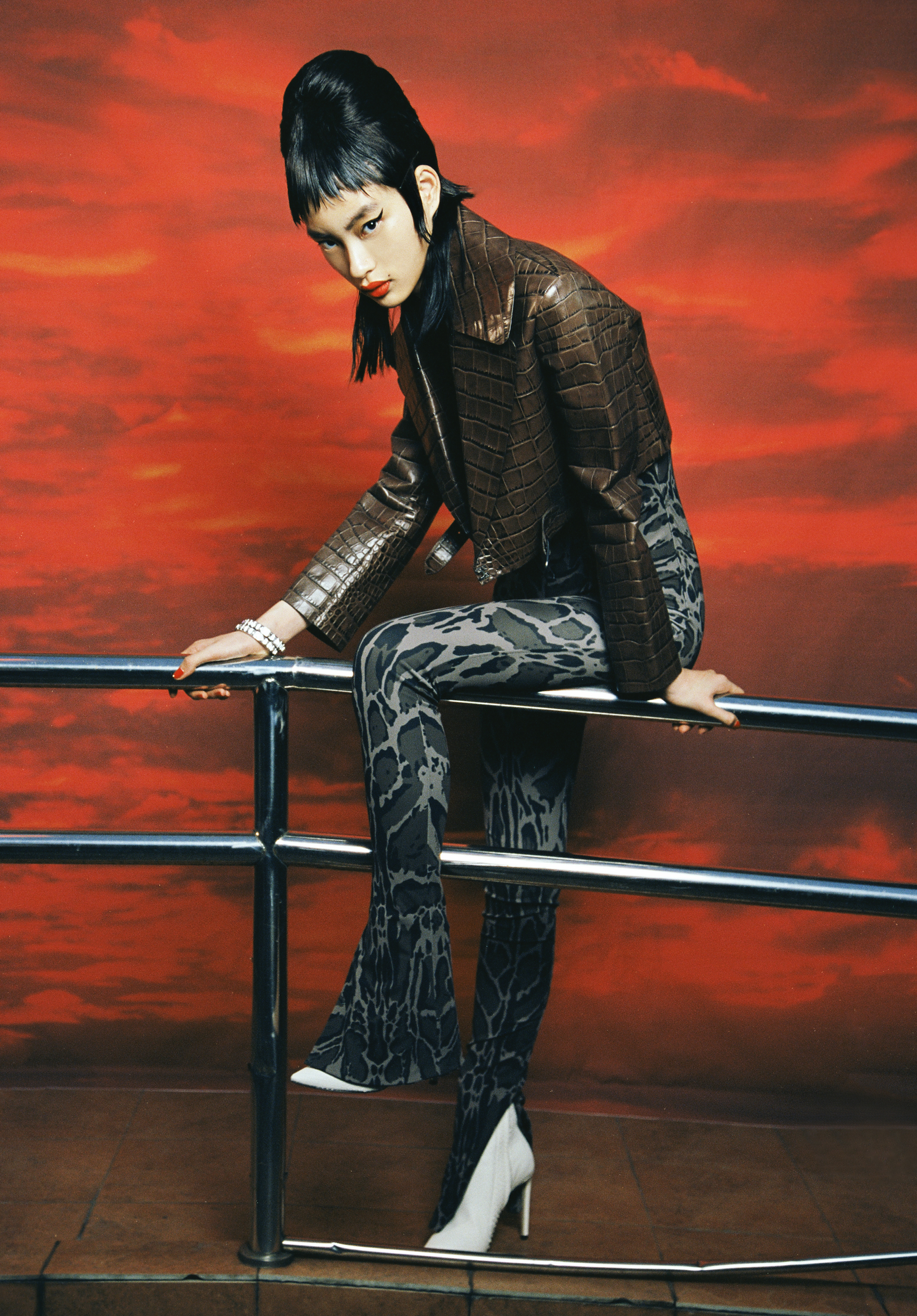 Brown crocodile leather jacket and grey leopard-print jumpsuit by Roberto Cavalli; White leather booties by Jimmy Choo; Bracelet by Swarovski