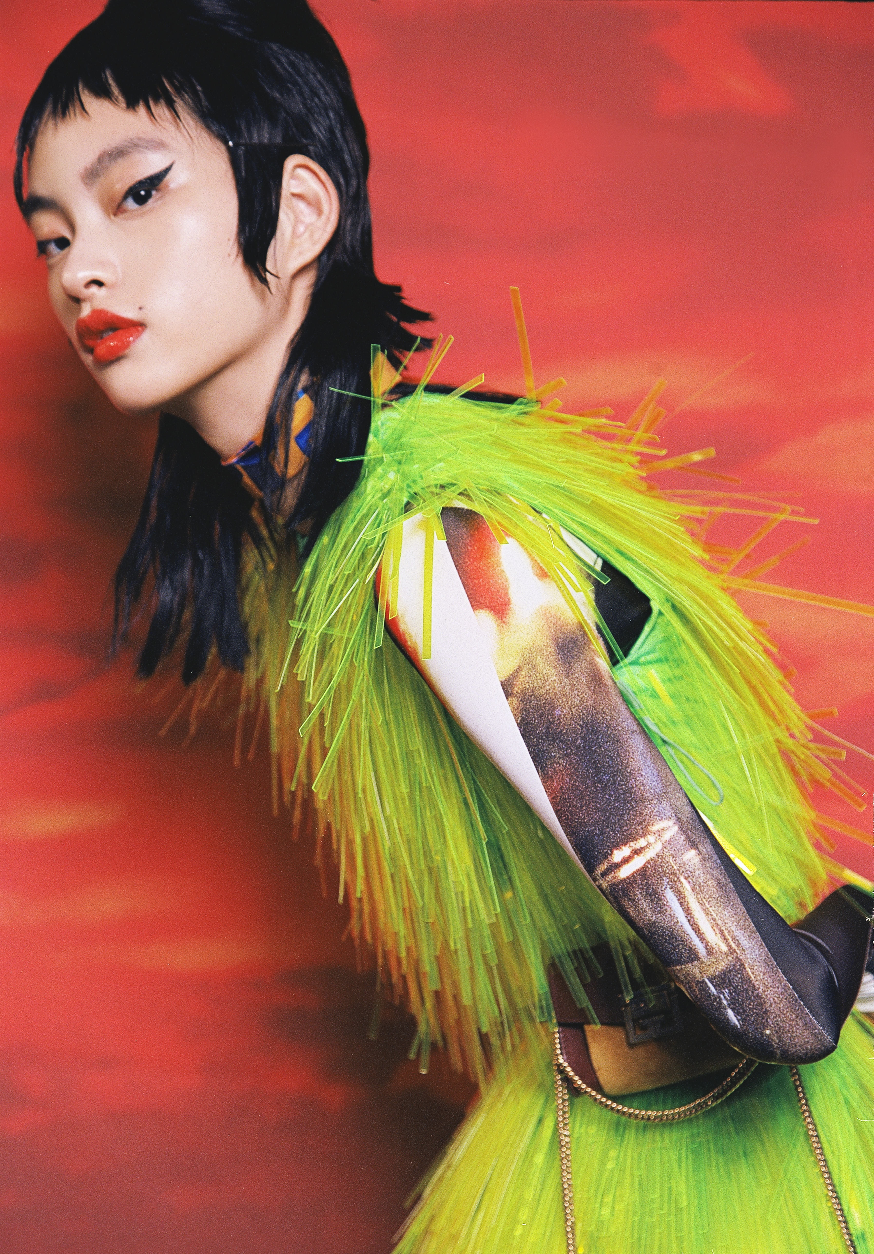 Yellow and blue scarf by Hermès; Green plastic-embellished dress by Prada; Top by Idism; Brown and yellow handbag by Givenchy