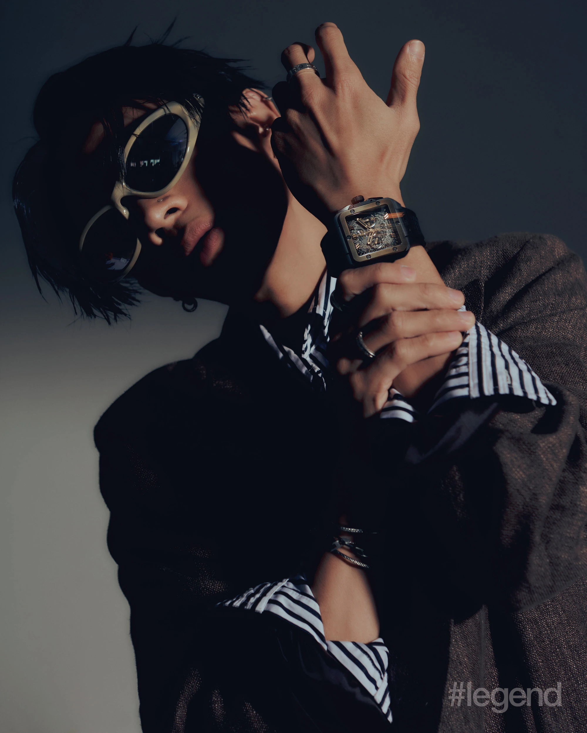 Brown double breasted linen and cotton blended blazer _ Our Legacy; Black striped cotton front button shirt _ Marc Jacobs; Ivory horn bio-based injected nylon, with mirror silver lenses sunglasses _ Balenciaga; Silver 925 sterling silver with rhodium coating mechanic claw ring _ Midnightfactory; Square Bang Unico Magic Gold _ Hublot.